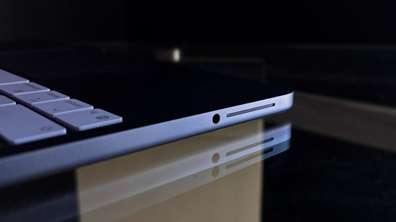 Foto miring dari speaker kiri MacBook Neo dan jack headphone