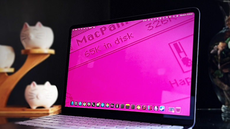 Gambar close-up layar MacBook Neo dengan wallpaper berwarna merah jambu cerah