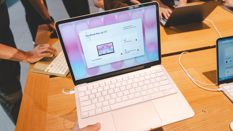 person holding a macbook neo inside a store