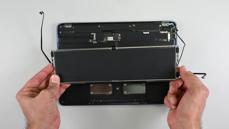 removing the battery from a macbook neo placed on a white table