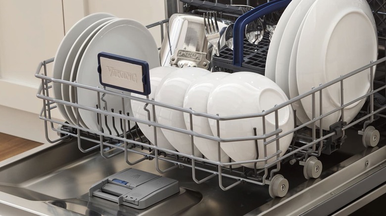 An open Viking built-in dishwasher filled with dishes in a white kitchen.