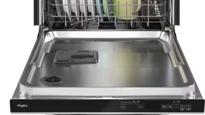 An open Whirlpool dishwasher filled with various dishes and cutlery.