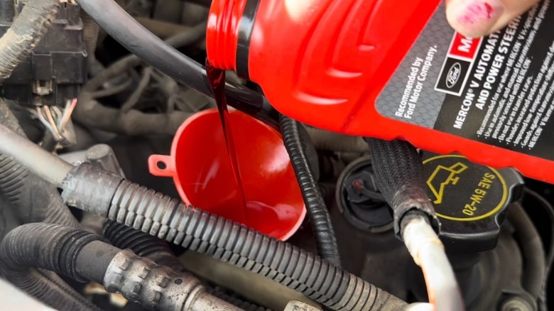 A person adding transmission fluid to their f150 pickup truck