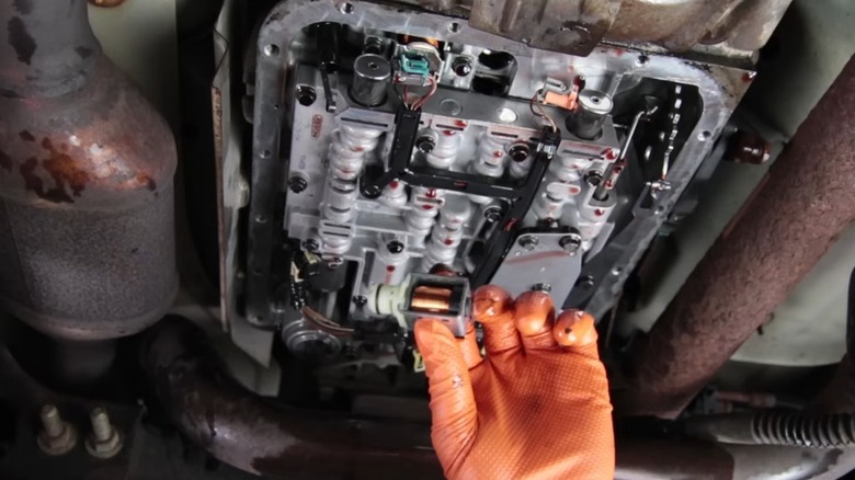 A person replacing their transmission shift solenoids