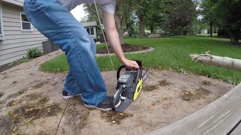 A man pulling the starter cord for a Ryobi 14-inch 37cc 2-cycle gas chainsaw