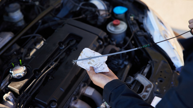 Close-up shot of a mechanic holding a dipstick while checking the oil levels of a car
