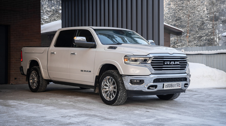A white Dodge Ram 1500 pulling out of an industrial building.