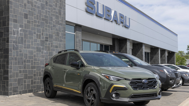 A lineup of Subaru cars outside a Subaru dealership.