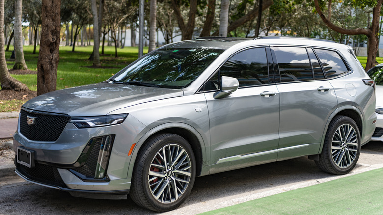 A gray Cadillac XT6 parked beside an array of trees.