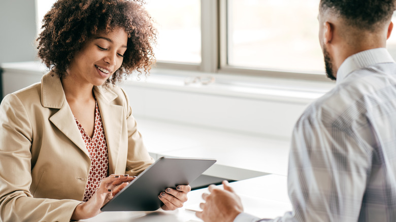 Woman interviewing man while using iPad