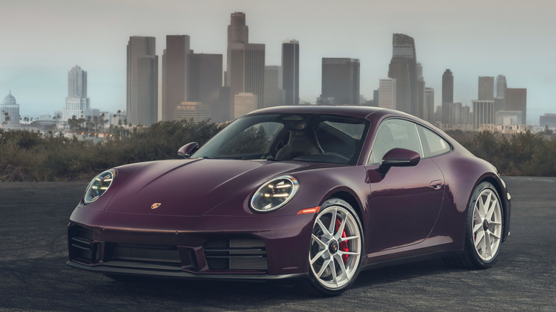 Front 3/4 view of 2027 Porsche 911 Carrera S parked with city in background