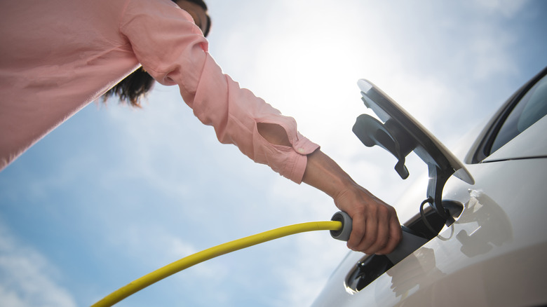 person plugging in EV charging port