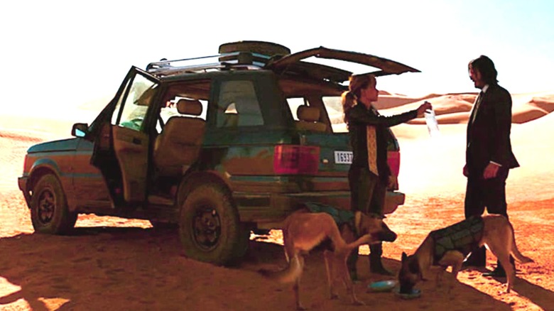 Sofia Al-Azwar holding out a bottle of water to John Wick in front of her 1995 Range Rover in "John Wick: Chapter 3 - Parabellum"