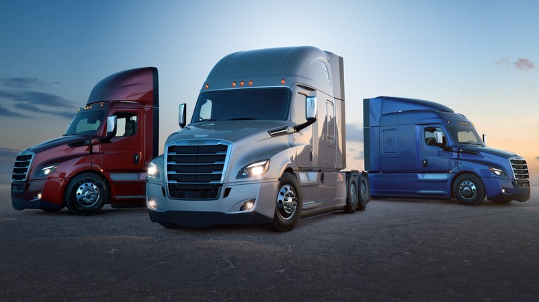 Red, silver, and blue Freightliner Cascadias parked
