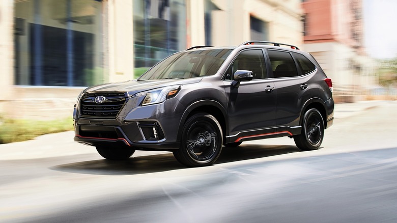 2024 Subaru Forester Sport driving down city street next to a building