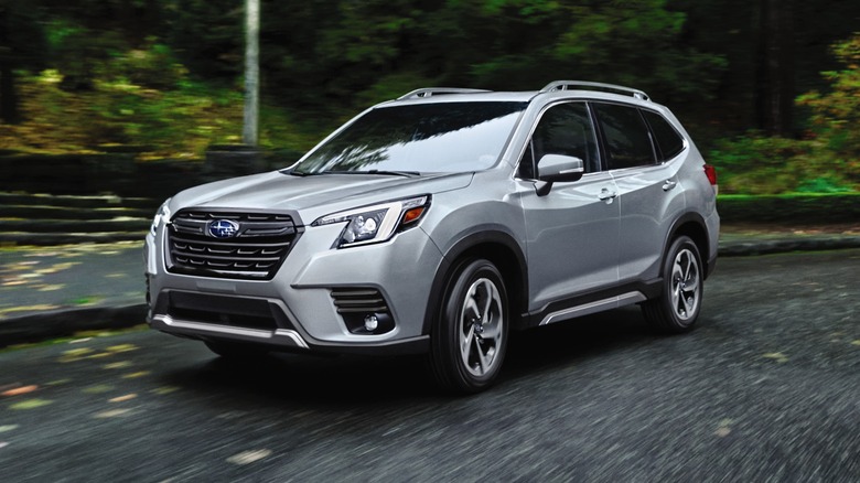 2024 Subaru Forester driving around a turn with trees in the background
