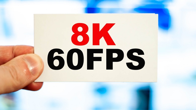 Someone holding up a card with "8K 60FPS" on the screen