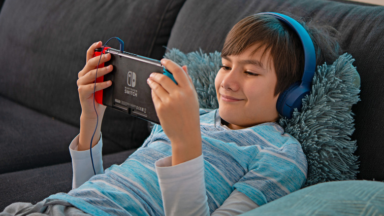 Kid playing Nintendo Switch with headphones