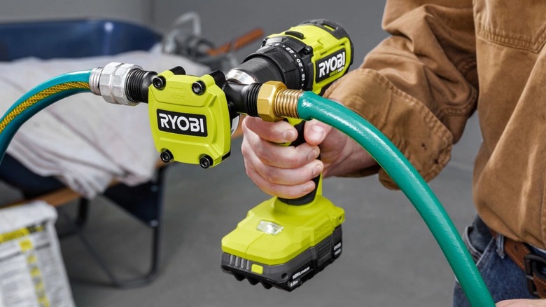 Person holding Ryobi drill with pump attachment