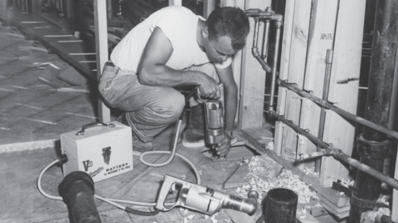 Worker using early 20th-century Milwaukee battery-powered tool