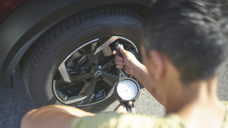 Man checking tire pressure in car