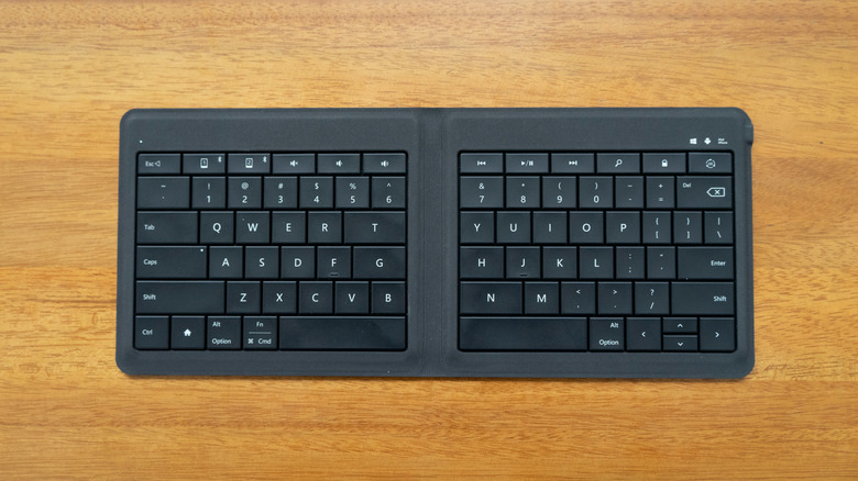 A black bi-fold foldable keyboard placed on a wooden surface