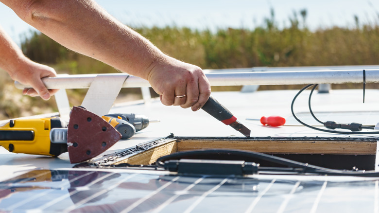 Hand installs solar panel using kit on camper van