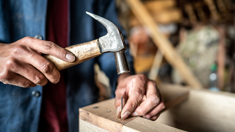 man hammering nail into wood