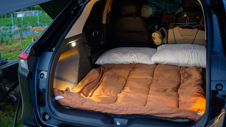A sleeping mat set up in the back of an SUV.