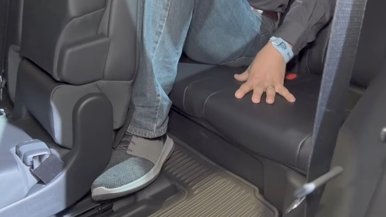 An Adult Sitting In A Cramped Third-Row Seat