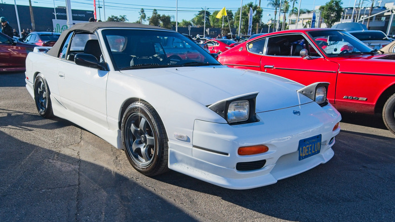 Front three-quarter view of a white Nissan 240SX convertible parked at a car show.