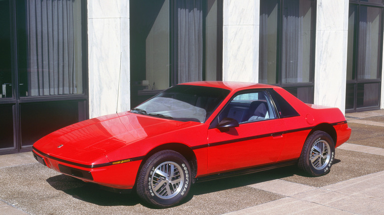 Red Pontiac Fiero on display in front of building