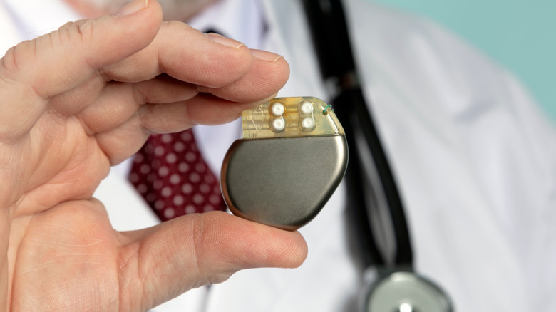 physician holds up pacemaker