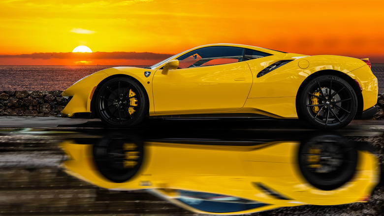 Yellow Ferrari parked against sunset
