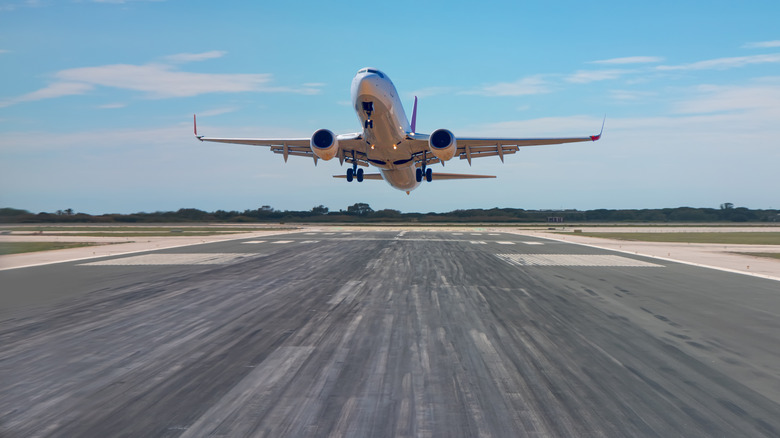 A passenger plane taking off airport with tire tracks from previou airplane tires left marks on the runway.