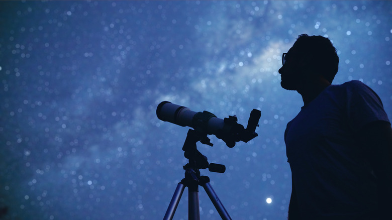 Man with a telescope looking into the night sky