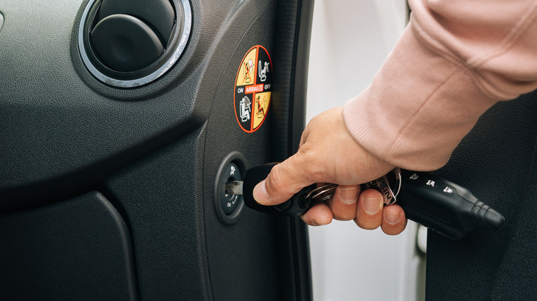 man turning off car passenger air bag with key