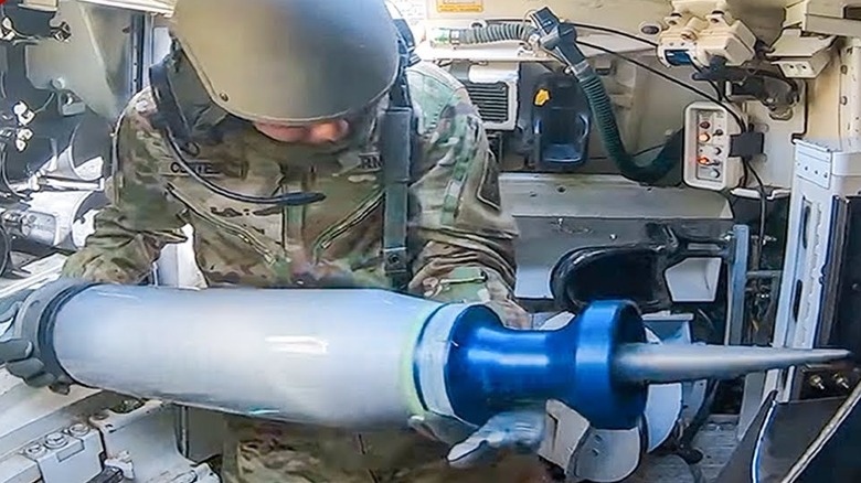 Close up of a U.S. Army tank loader loading ammunition into the main barrel from inside the tank.