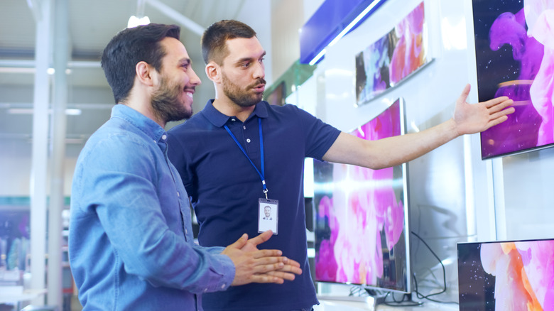 Retail store assistant shows customer a TV
