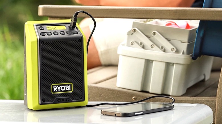 Person charging their mobile device while listening to Ryobi Bluetooth Speaker