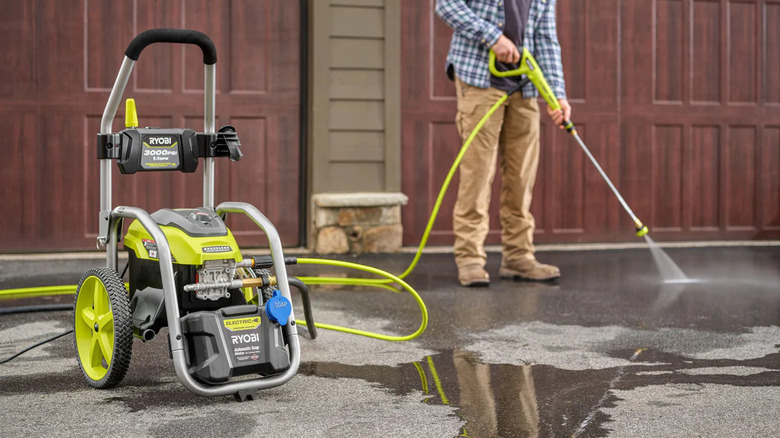 A man wearing a brown trouser cleaning his driveway with a Ryobi pressure washer