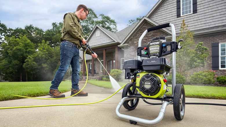 A man using a ryobi 2000 PSI 2.5 GPM Pressure Washer to clean his sidewalk