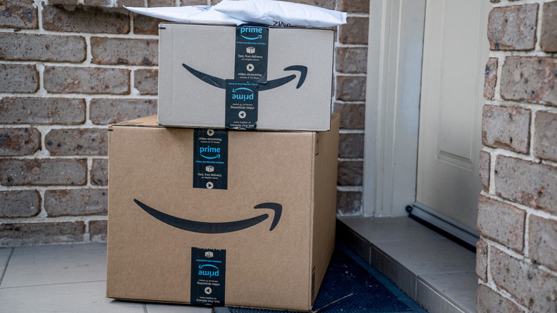 Amazon boxes and a package left outside somebody's front door, brick walls in the background