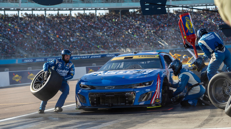 NASCAR pit crew servicing tires on Chevrolet stock car, front-view