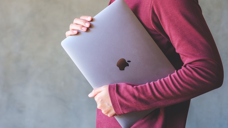 person carrying a macbook pro