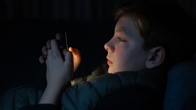 child on phone in darkness