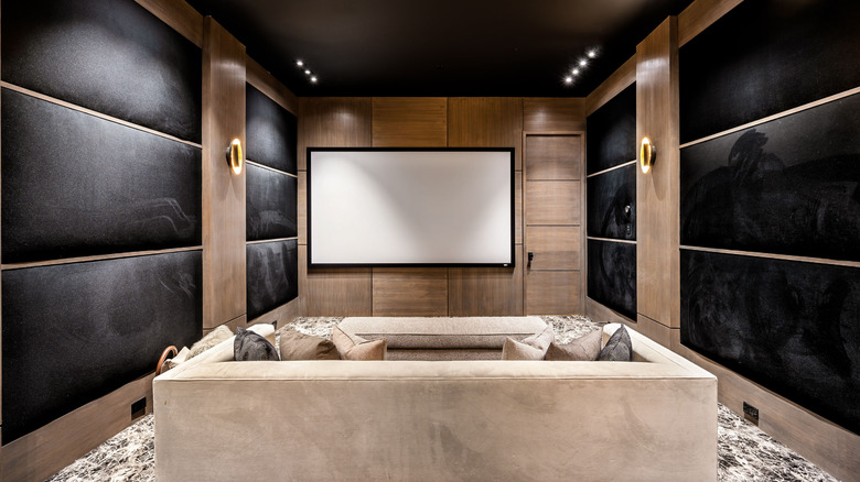 A modern home theater room with comfortable seating, a large screen, and elegant wood paneling