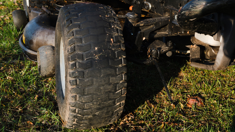 A worn rear tire of a lawn mower showing degraded tread