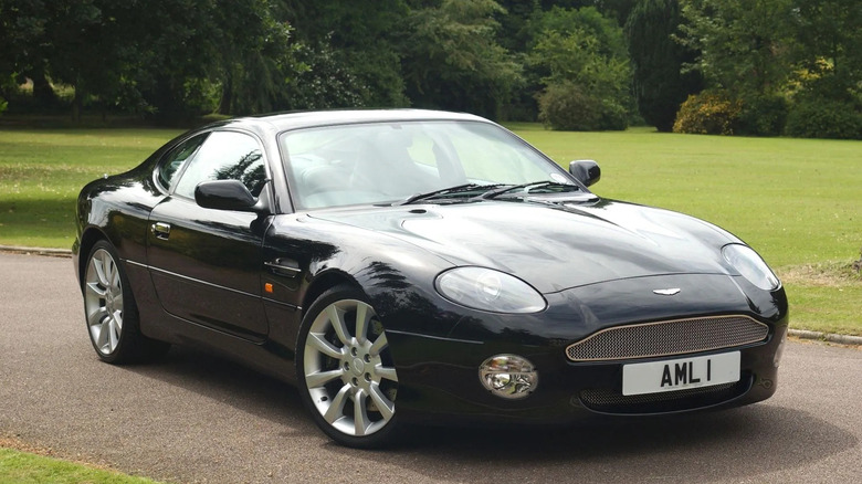 Aston Martin DB7 parked on pavement in front of a grassy lawn