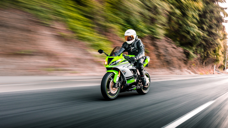 Person riding Kawasaki Ninja wearing full riding gear on mountain road